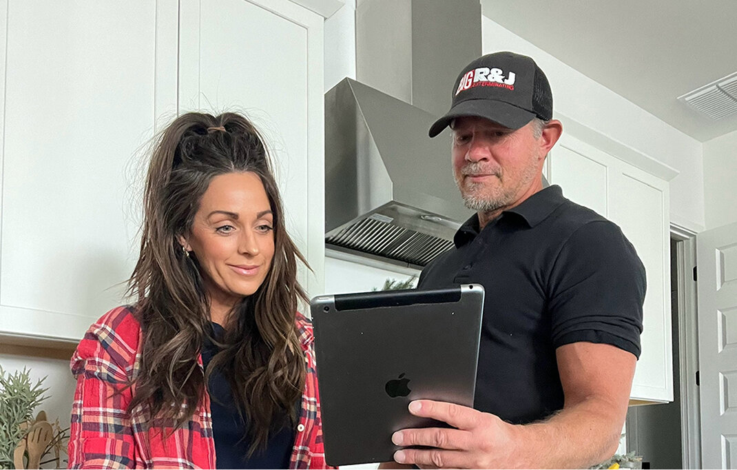 Big R&J technician reviews project details on an iPad with smiling woman client